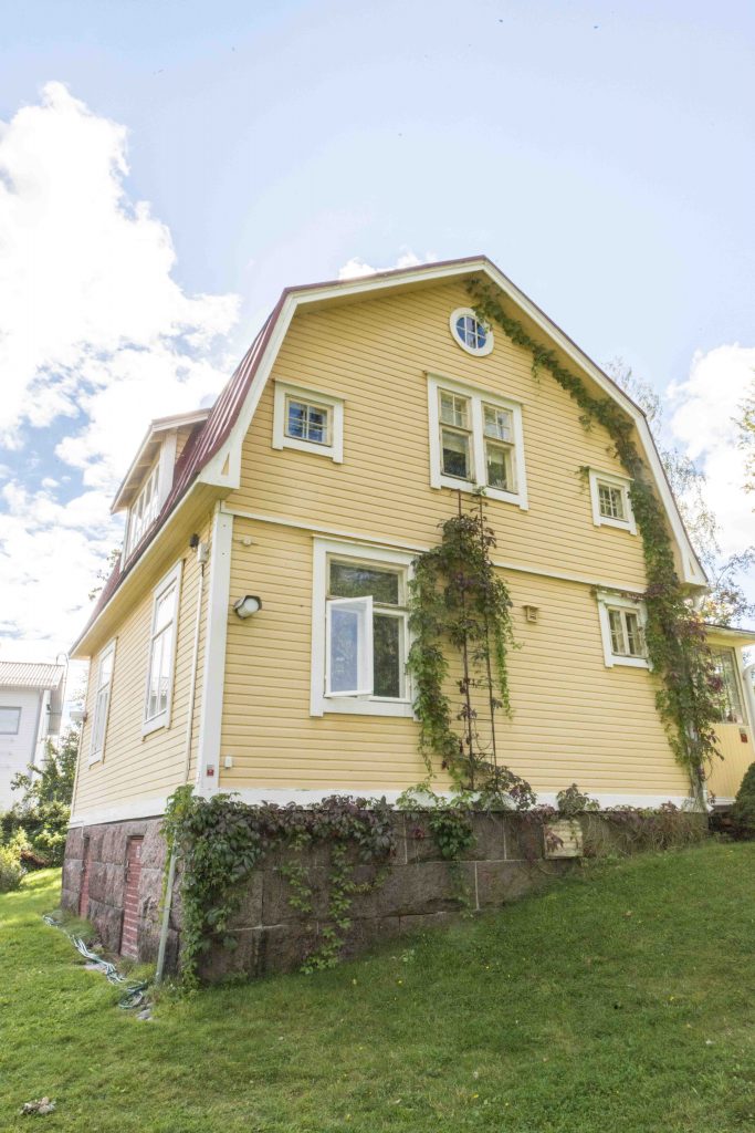 Kesäinen kuva keltaisesta kolmikerroksisesta omakotitalosta